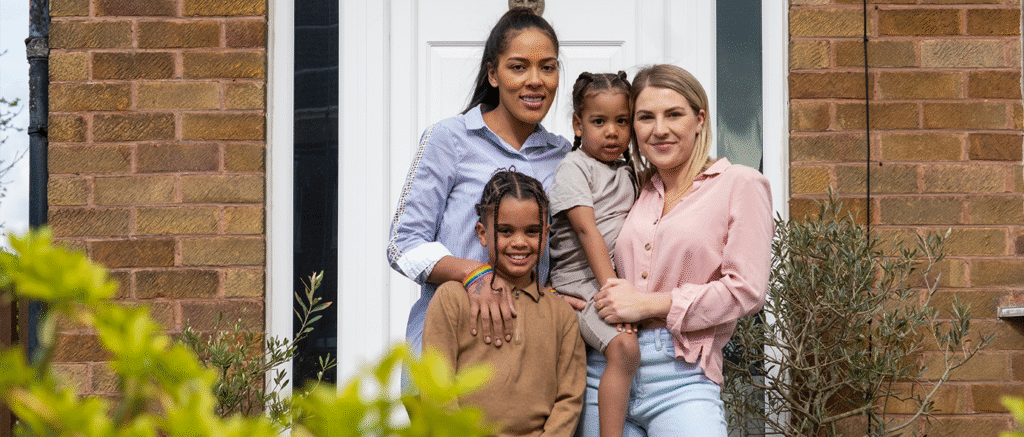 Happy family standing together at front door of their UK brick home